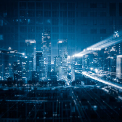 Aerial night view of a glowing city skyline with streaks of light and digital grid overlays, representing Pakistan's accelerating tech and startup ecosystem, where capital is concentrating in fintech, AI services, and cross-border ventures amid a selective post-2024 investment recovery.